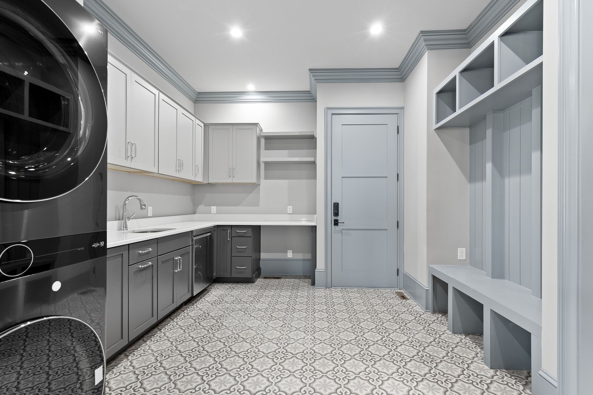 A laundry room with washer, cabinets, sink, patterned floor, and a built-in bench.