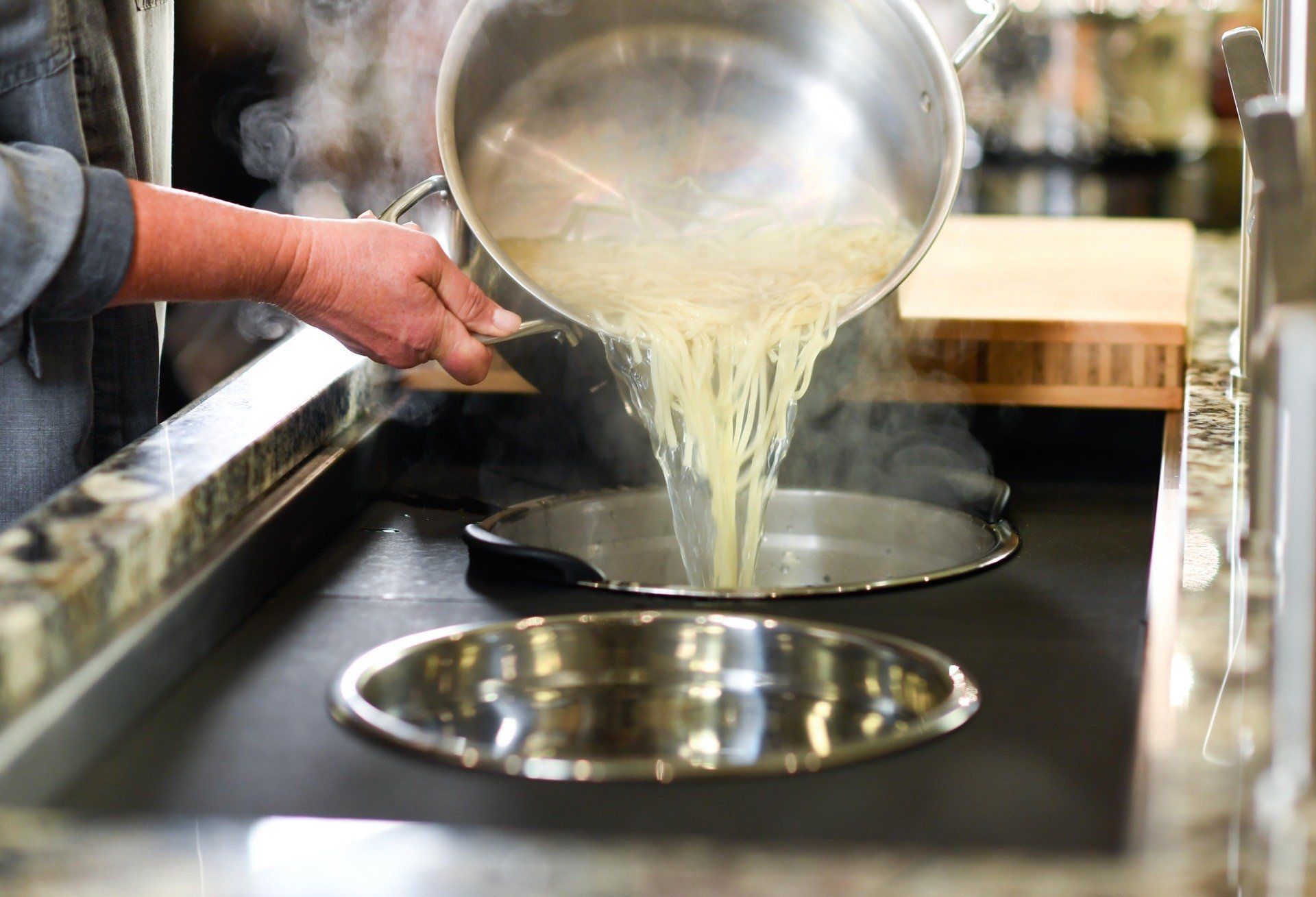 A person is pouring water into a pot on a stove.