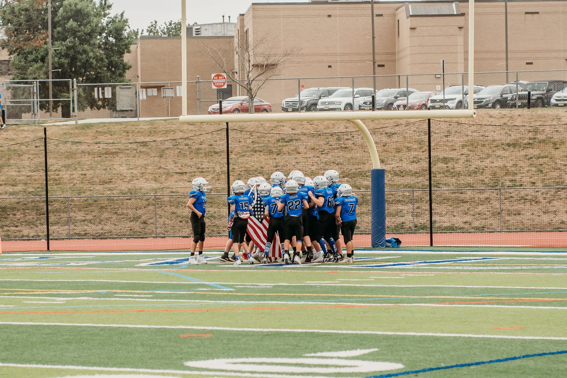 Football player in silver uniform runs with ball on a green field.