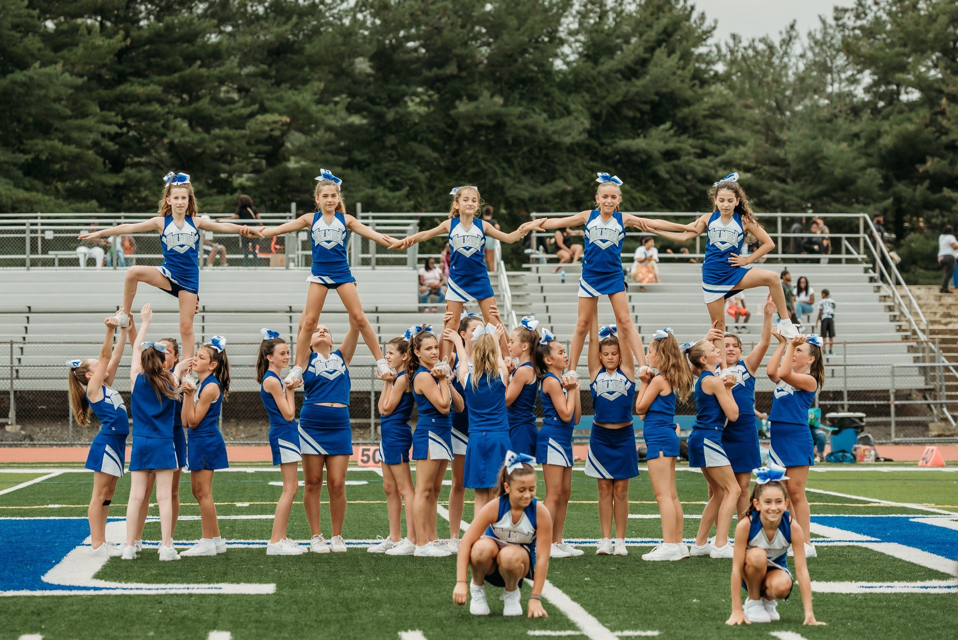 Cheerleader in red uniform performs a backbend on a green and red football field.