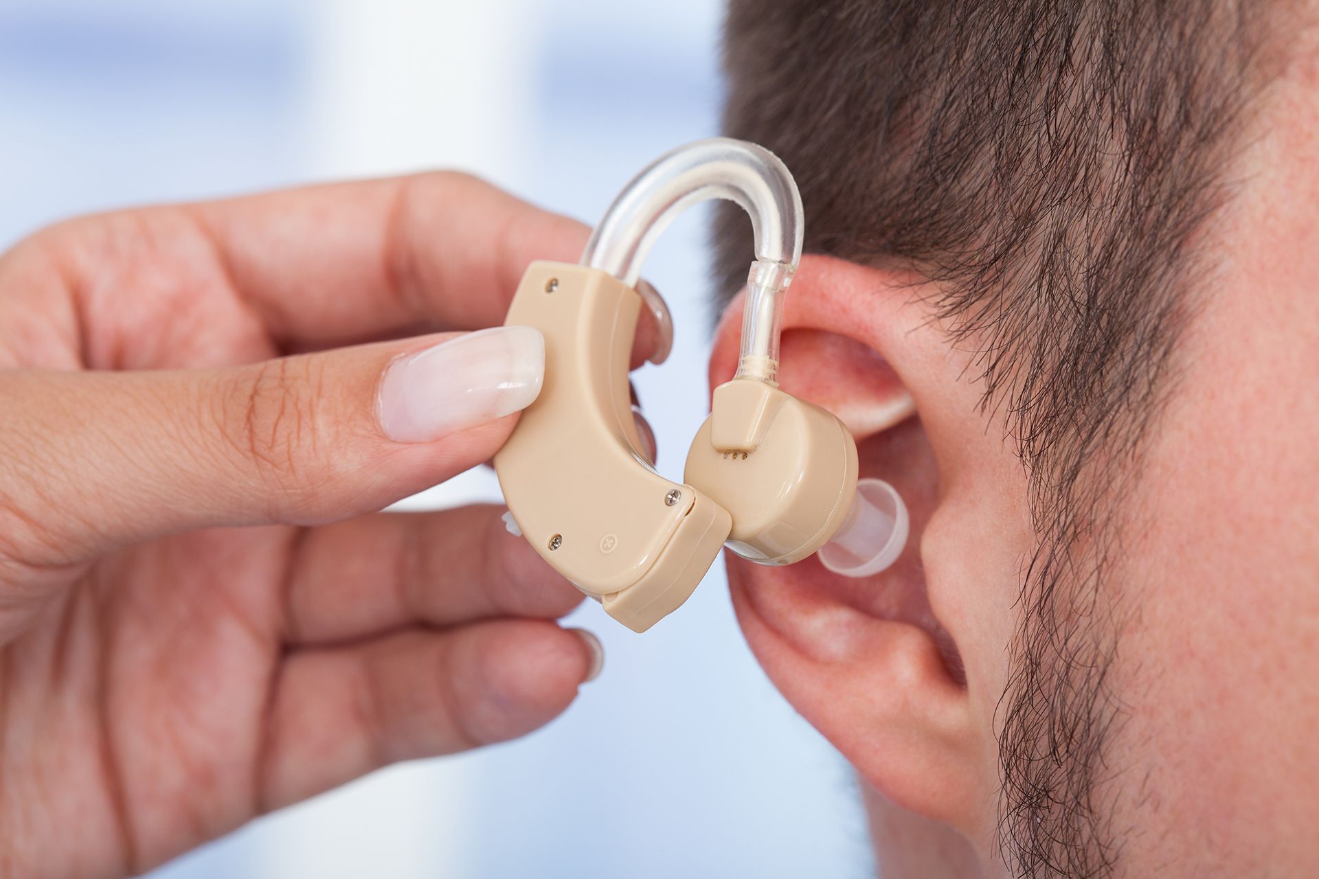 Putting New Hearing Aid on Man's Ear