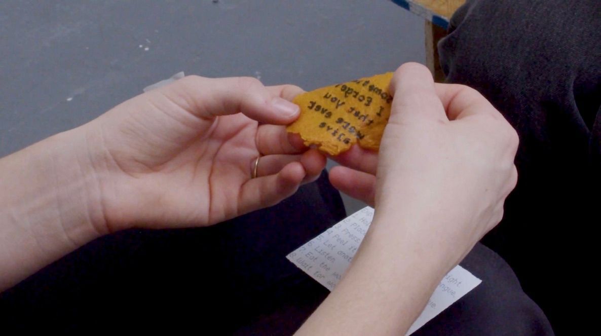 two hands hold a thin skin of fruit leather with backwards text printed on the surface. 