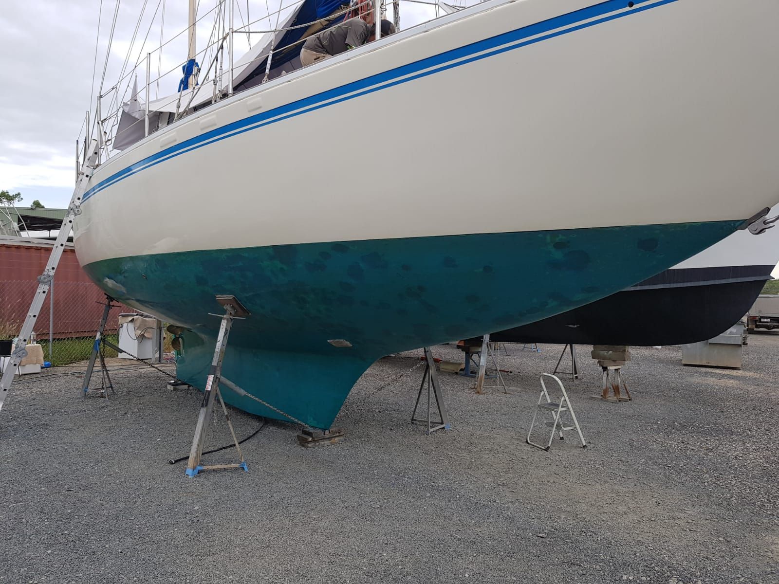 A White and Blue Sailboat is Sitting on a Gravel Lot — Baran Yachting in Redland Bay, QLD