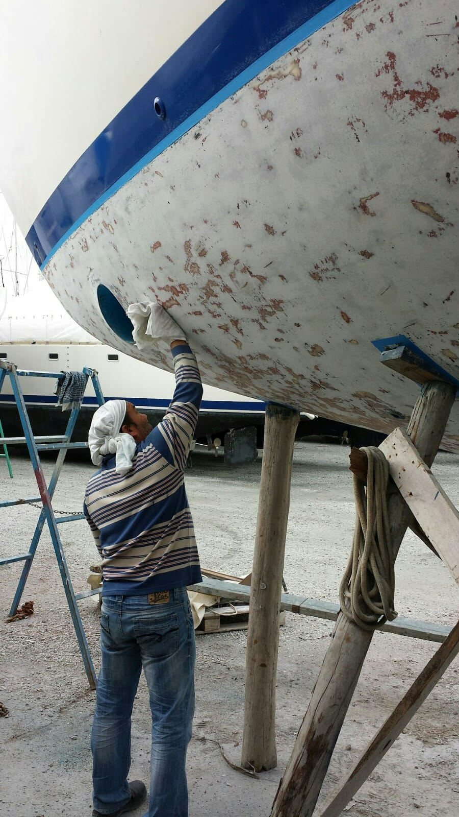 A Man Is Working On The Side Of A Boat — Baran Yachting In Coomera, QLD