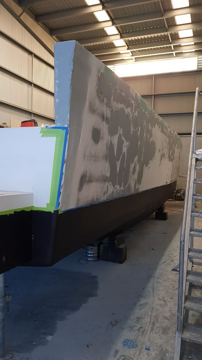 A Large Boat Is Being Painted In A Warehouse — Baran Yachting In Coomera, QLD