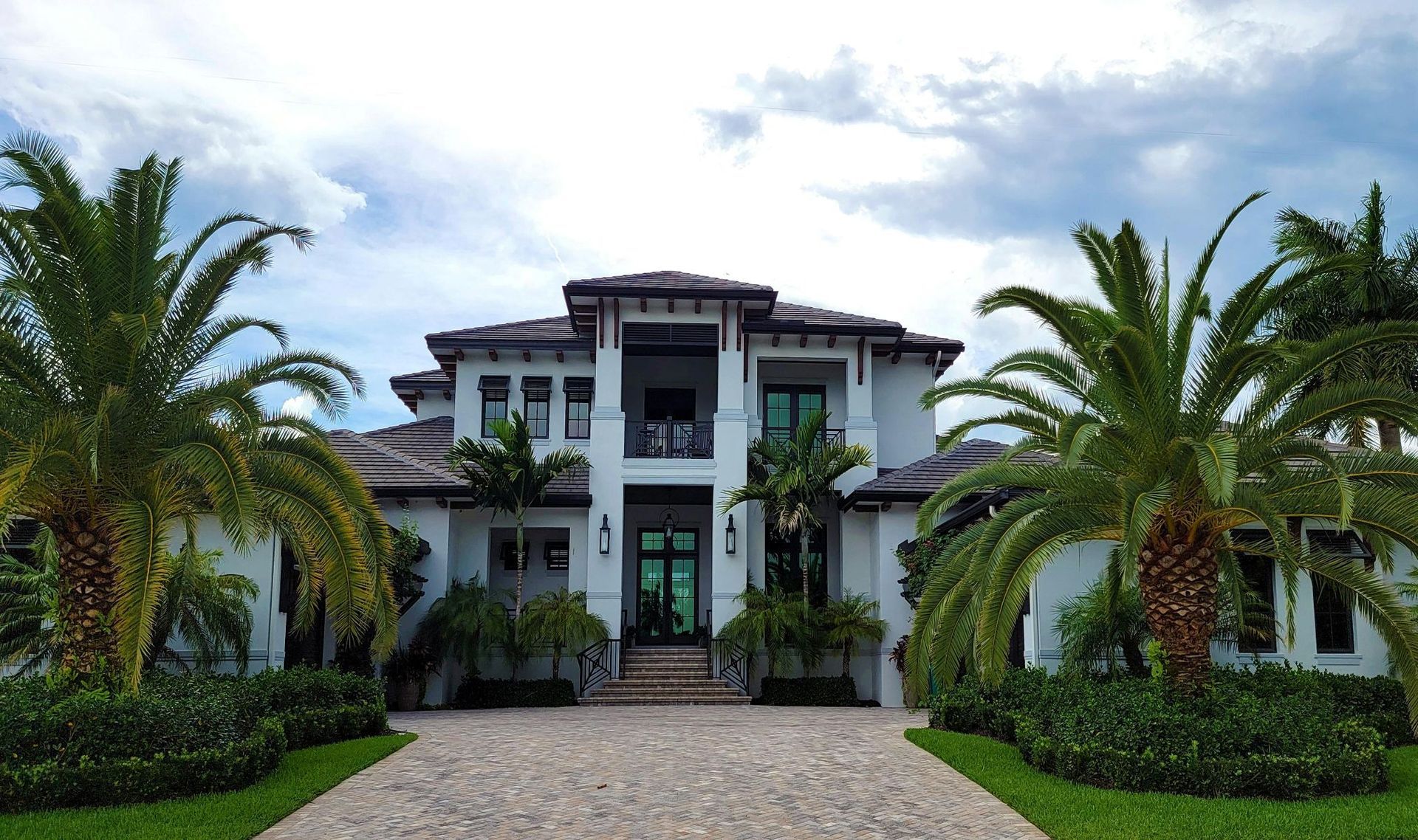 View of a modern suburban luxury house lined with palm trees on the side.