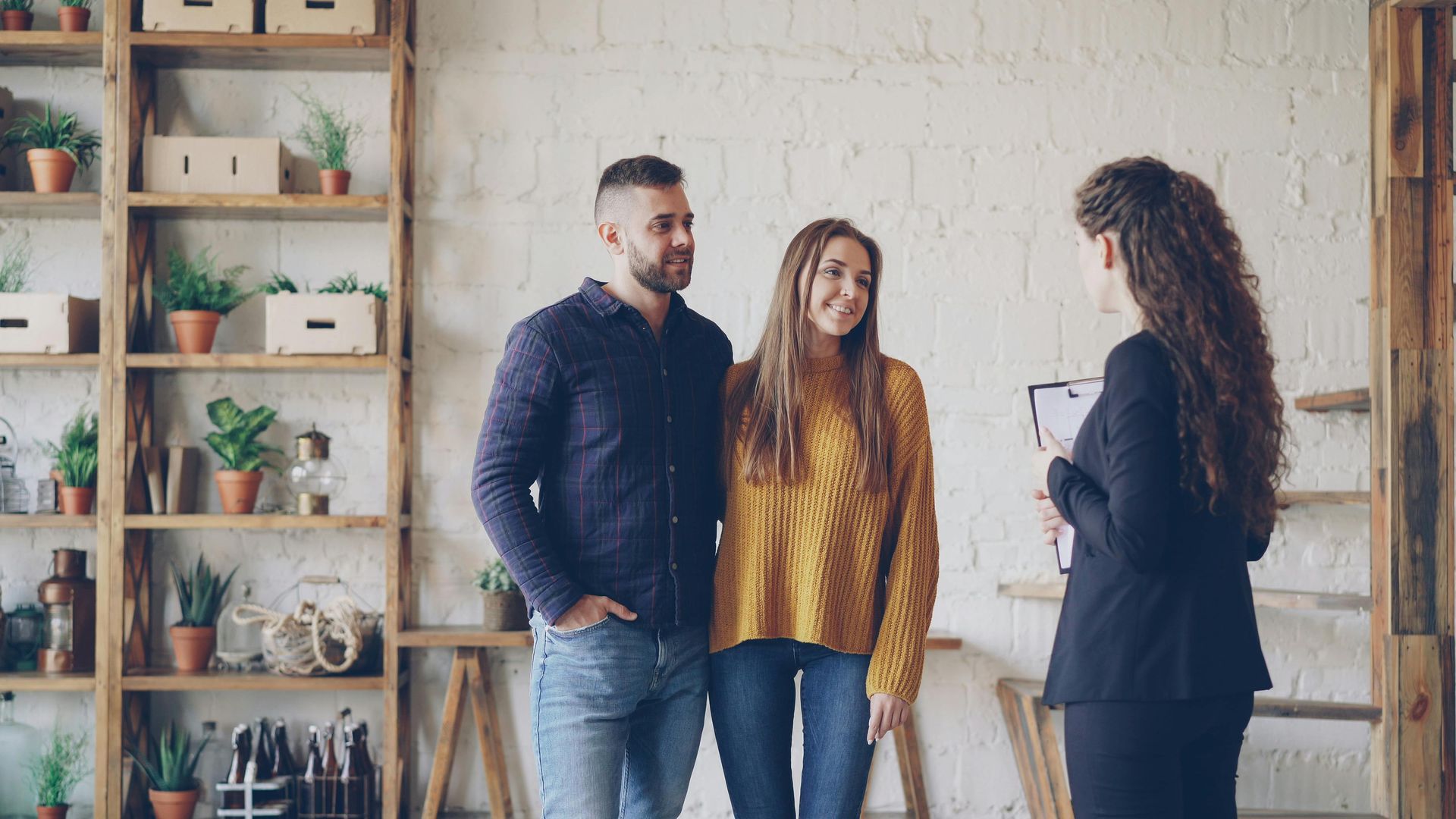 Three people talking in a bright office with shelves and potted plants