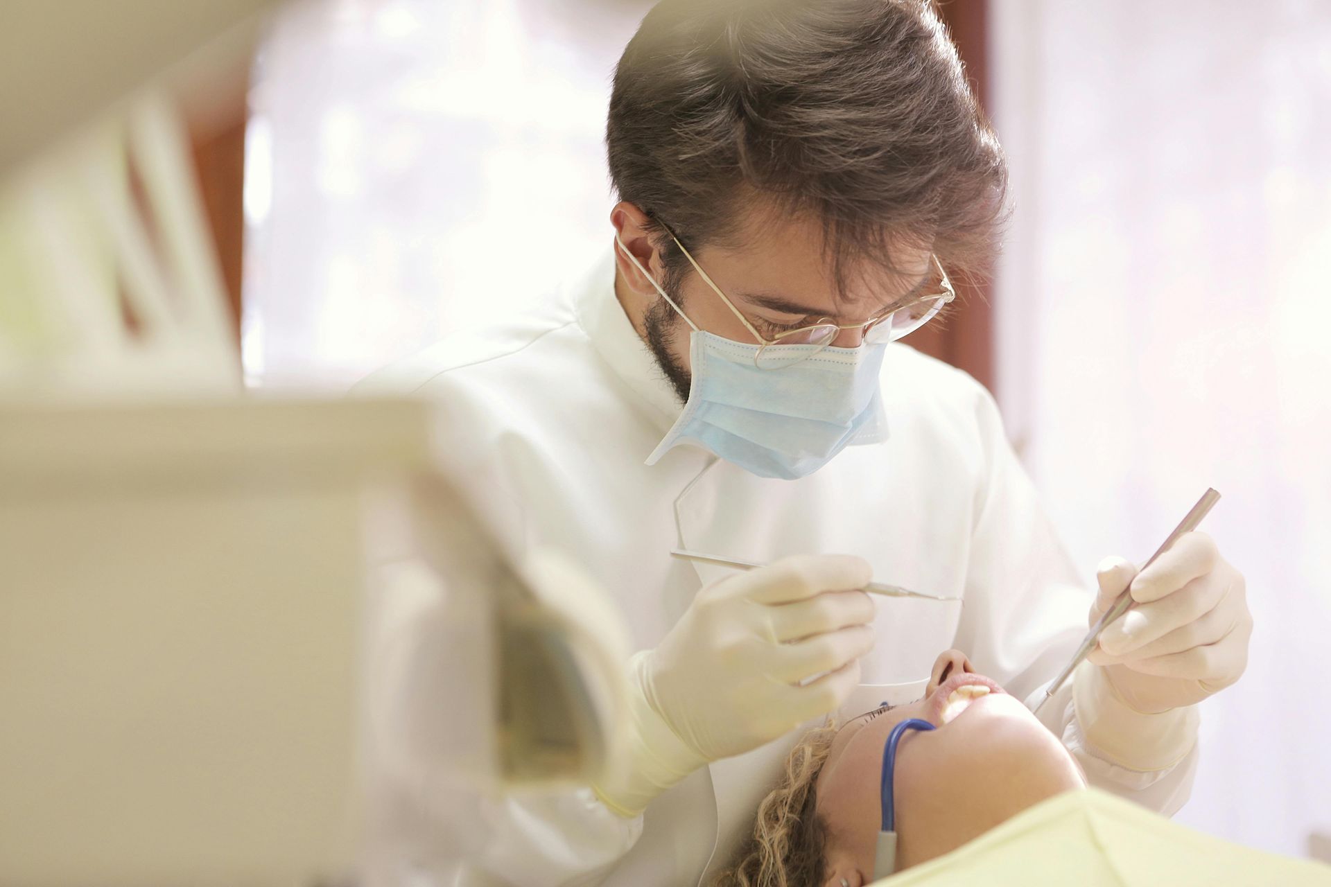 A male dentist checking teeth of a patient.