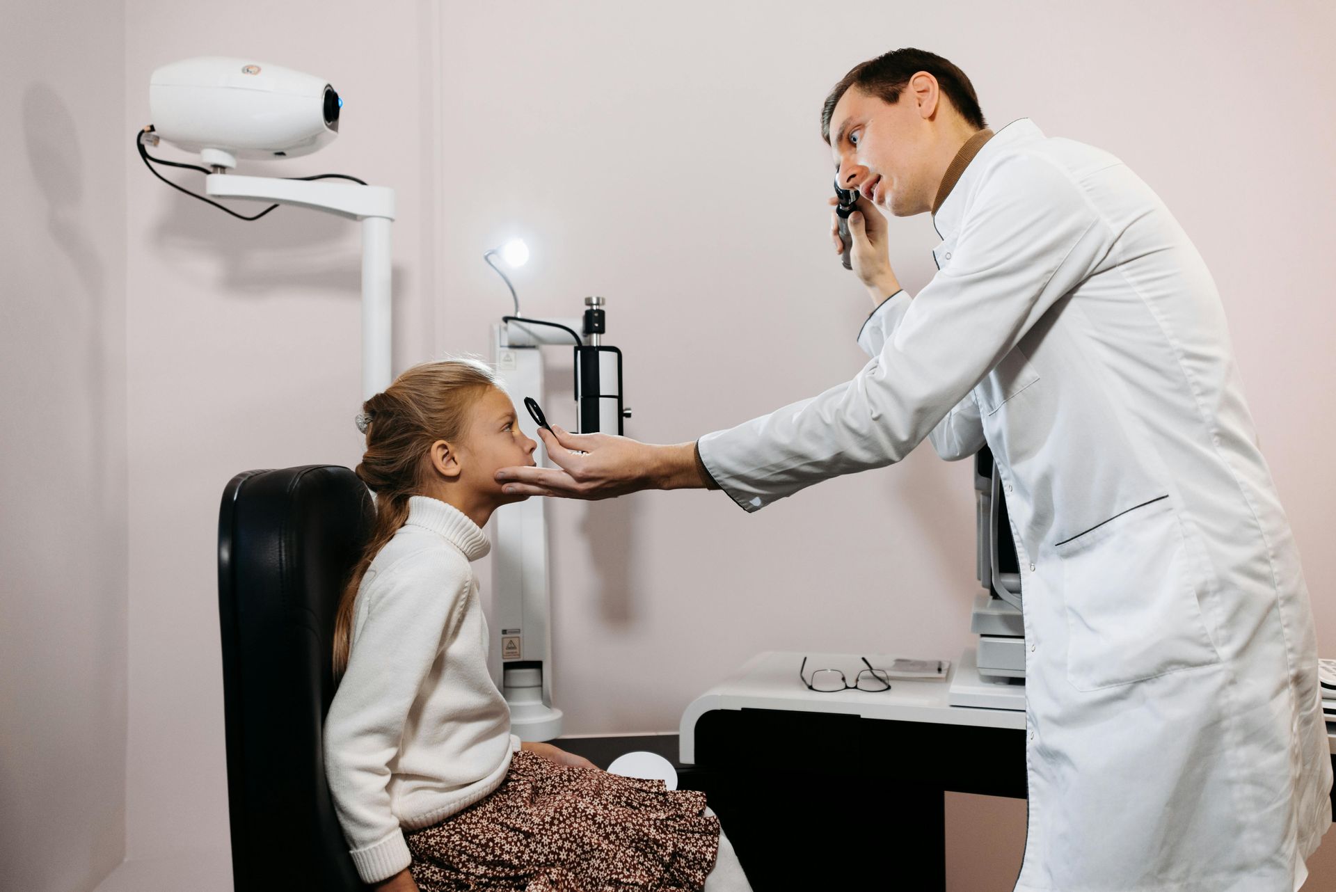 A male optometrist checking the eyes of a child patient.