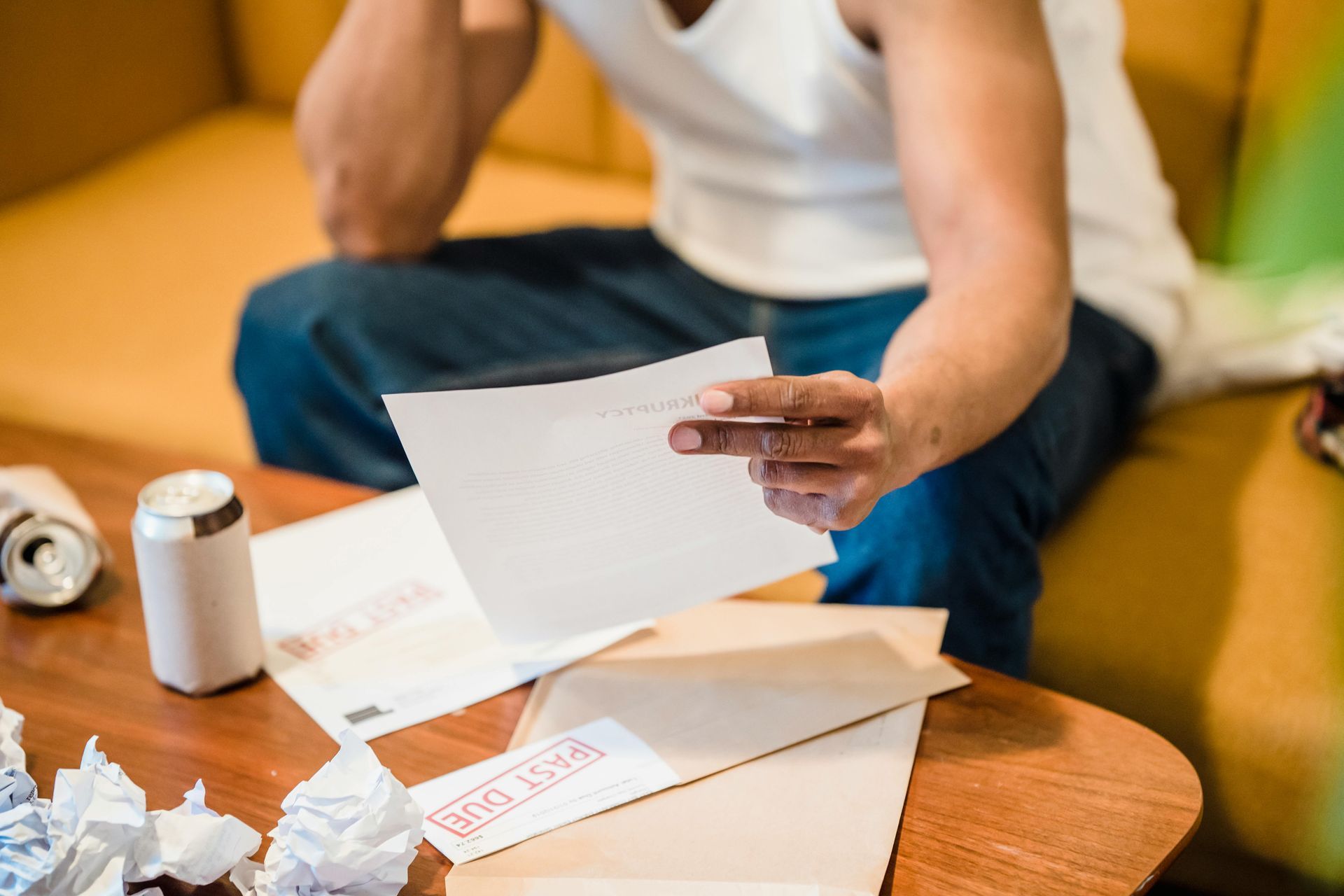 Person at a table sorting papers, with crumpled documents and a drink can nearby.