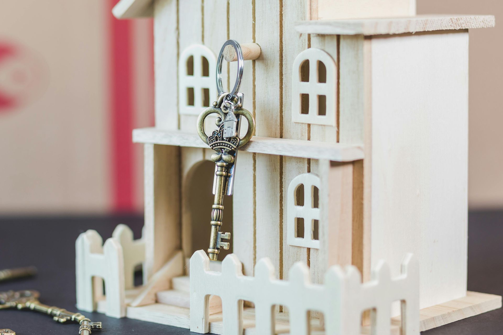 Miniature house model with a key in the front door and a white picket fence