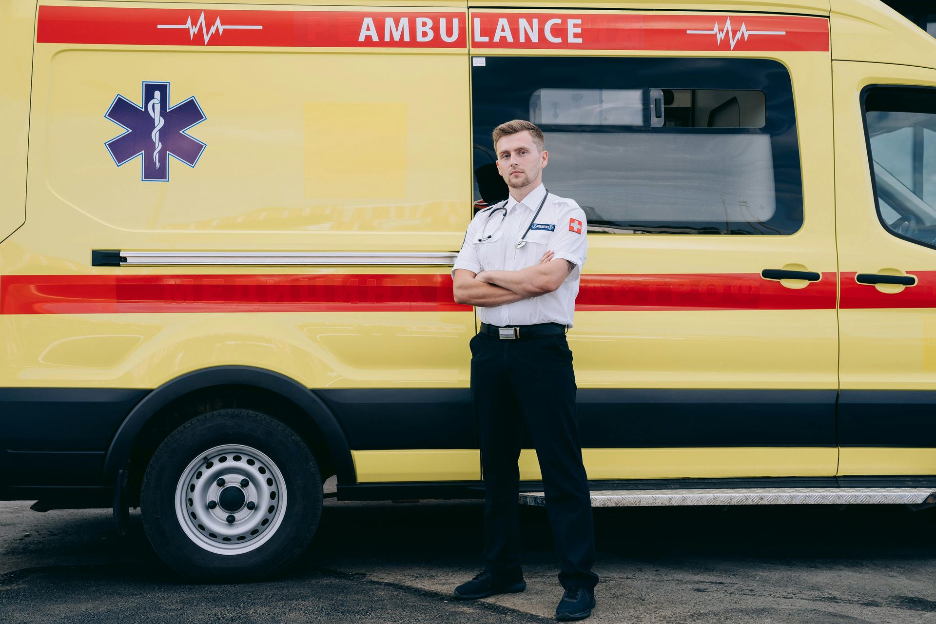 A male paramedic standing in front of an ambulance.