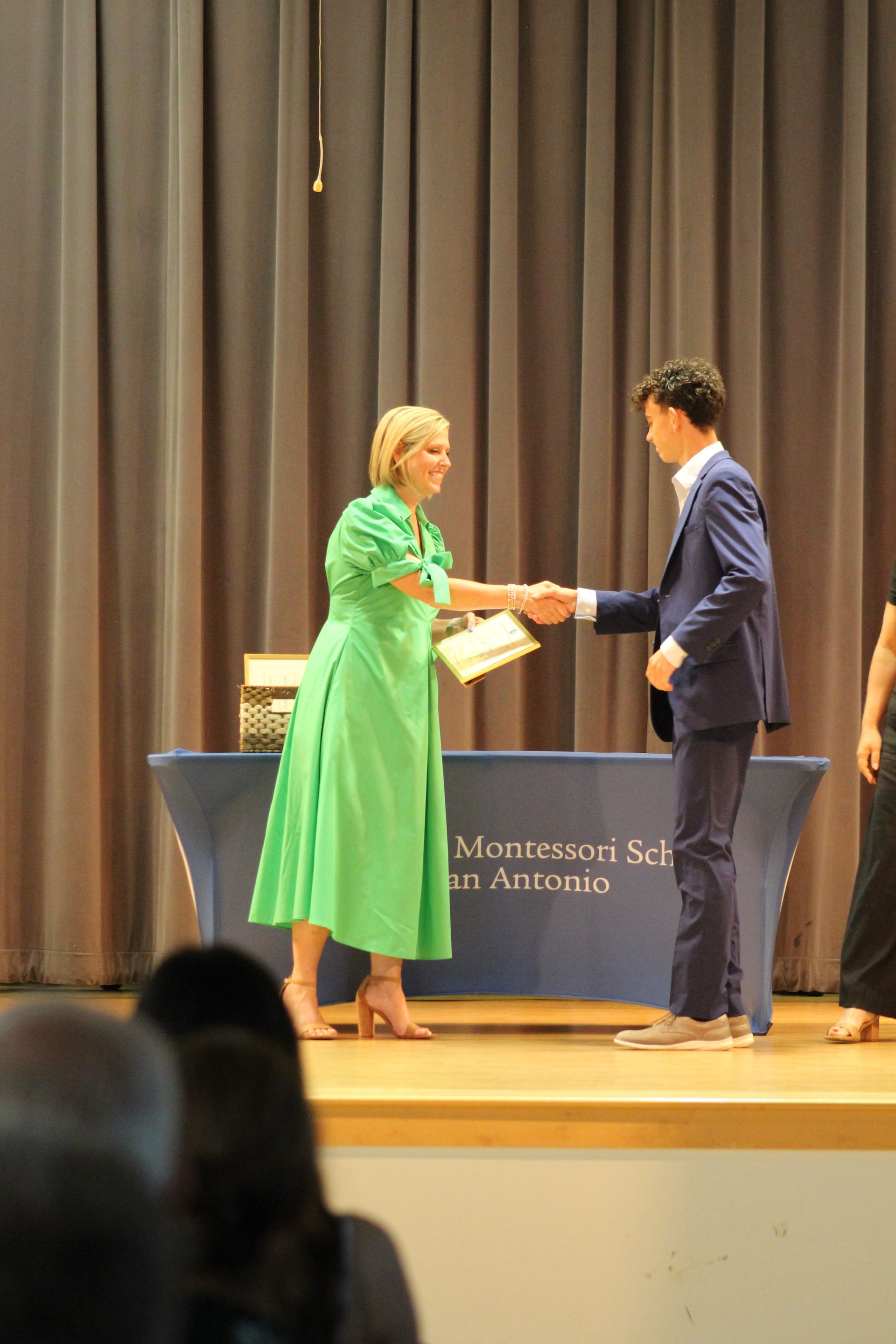 A graduate receiving his Certificat of Completion from the Head of School.