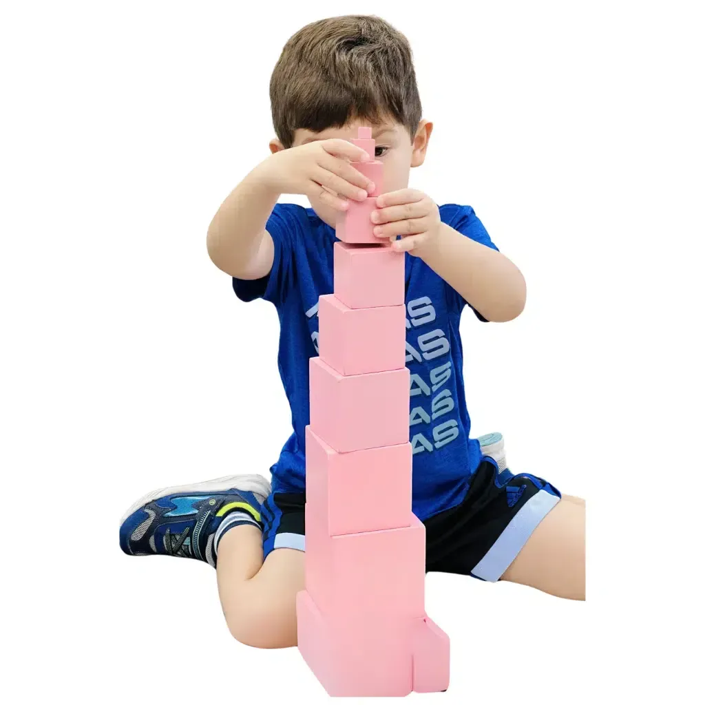 Young child stacking pink blocks into a tower.