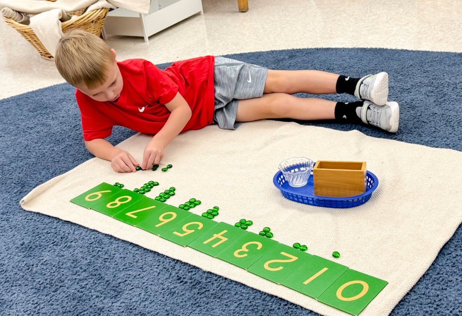 Boy lying on mat doing math with beads and number line.