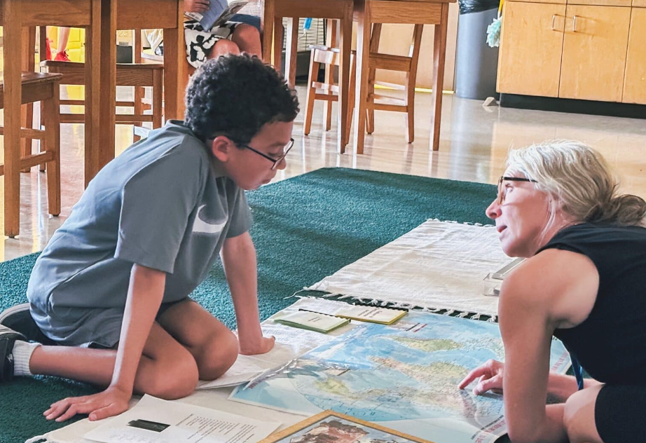 Boy and woman on floor looking at a world map. Indoors.