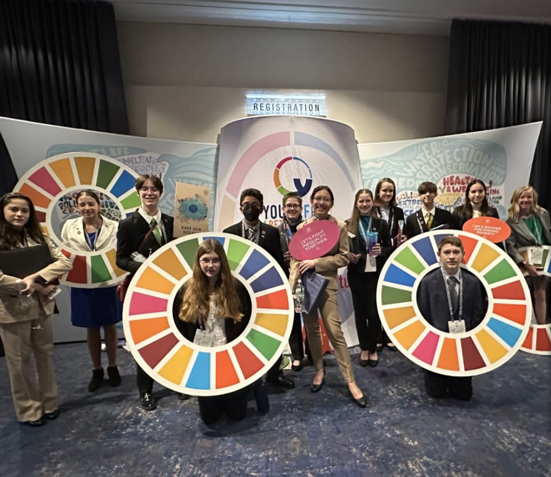 Group poses with colorful SDG rings at a Youth Forum event.