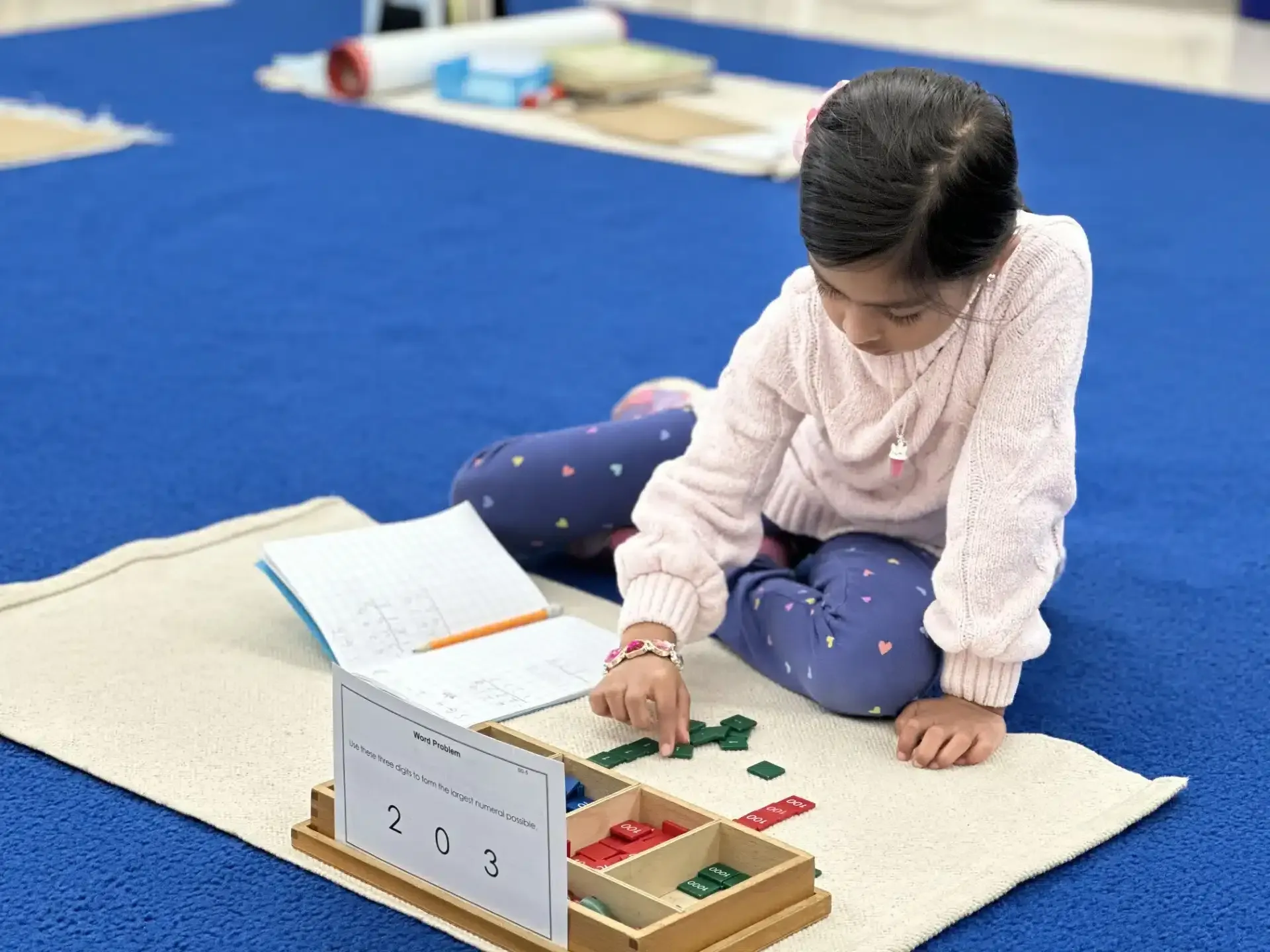 Girl using Montessori math materials on a mat. She sorts green and red blocks with a worksheet.