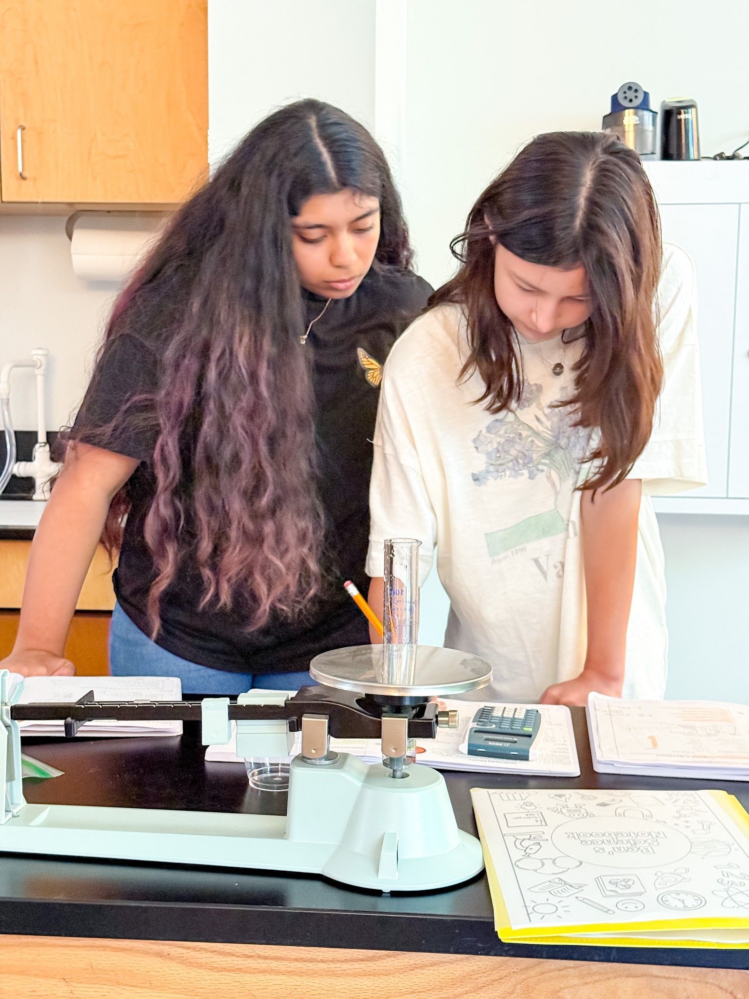 Girls using a calculator to determine surface area of a penny.
