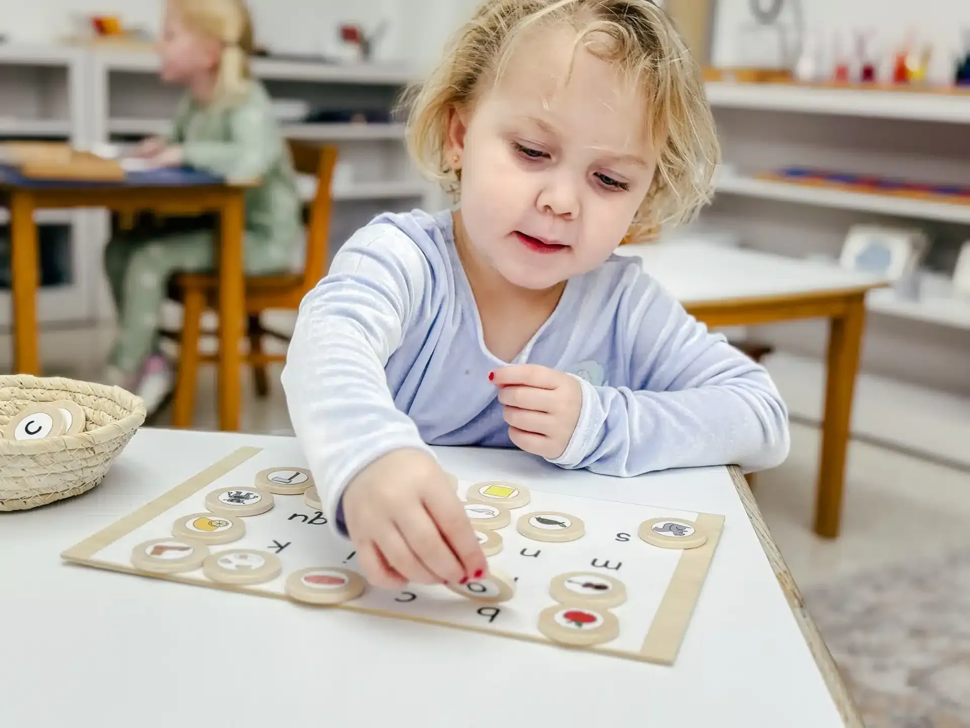 Young child at table playing a matching game with wooden circles and food illustrations.
