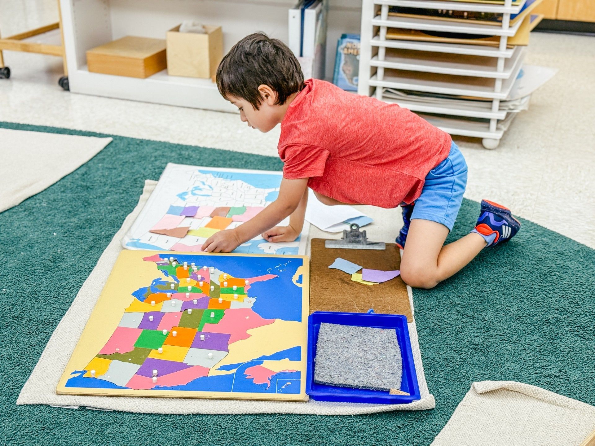 Boy recreating a map of the United States using state pieces and a laminated map.