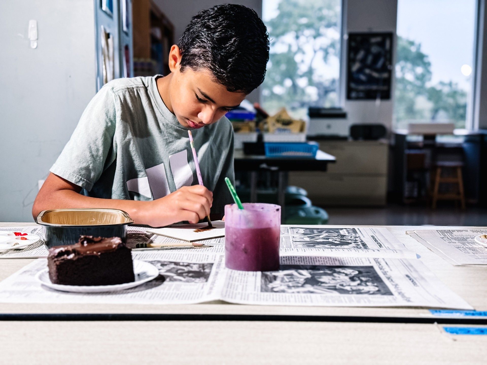 Boy focused on creating a painting of chocolate cake.