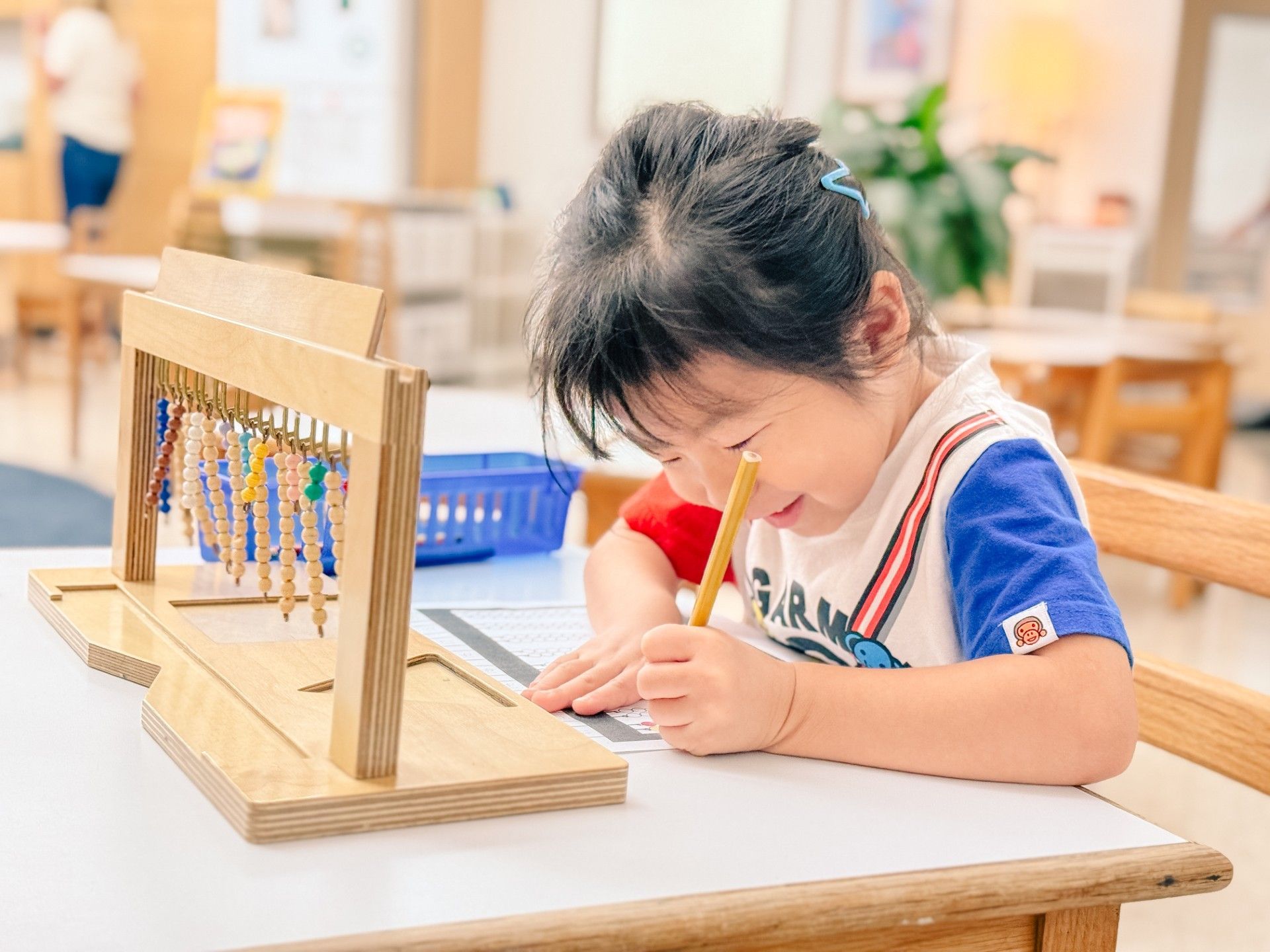 A young child is working with the teen bead hanger at a desk.