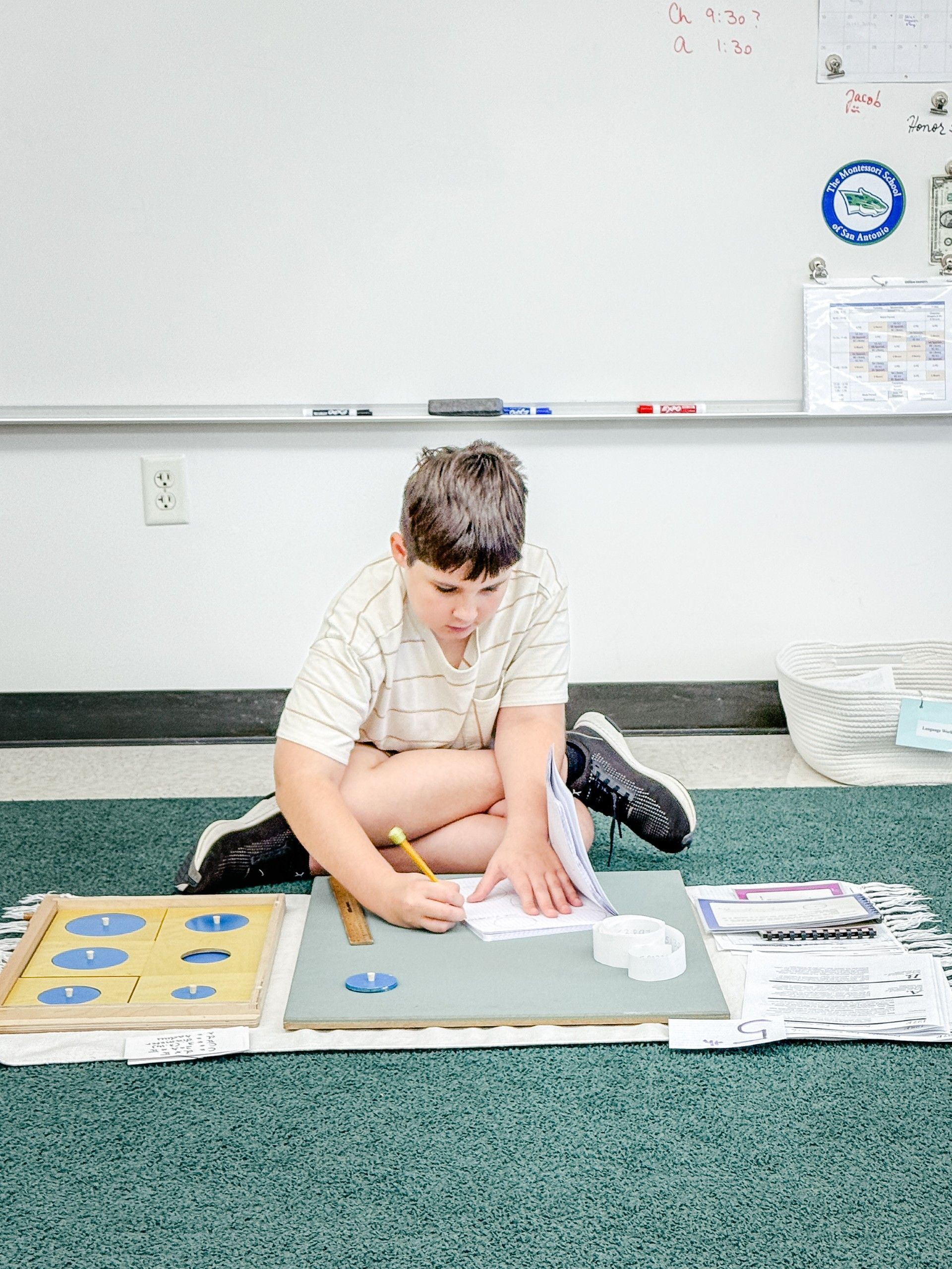 Boy on rug using insets to work fraction problems.