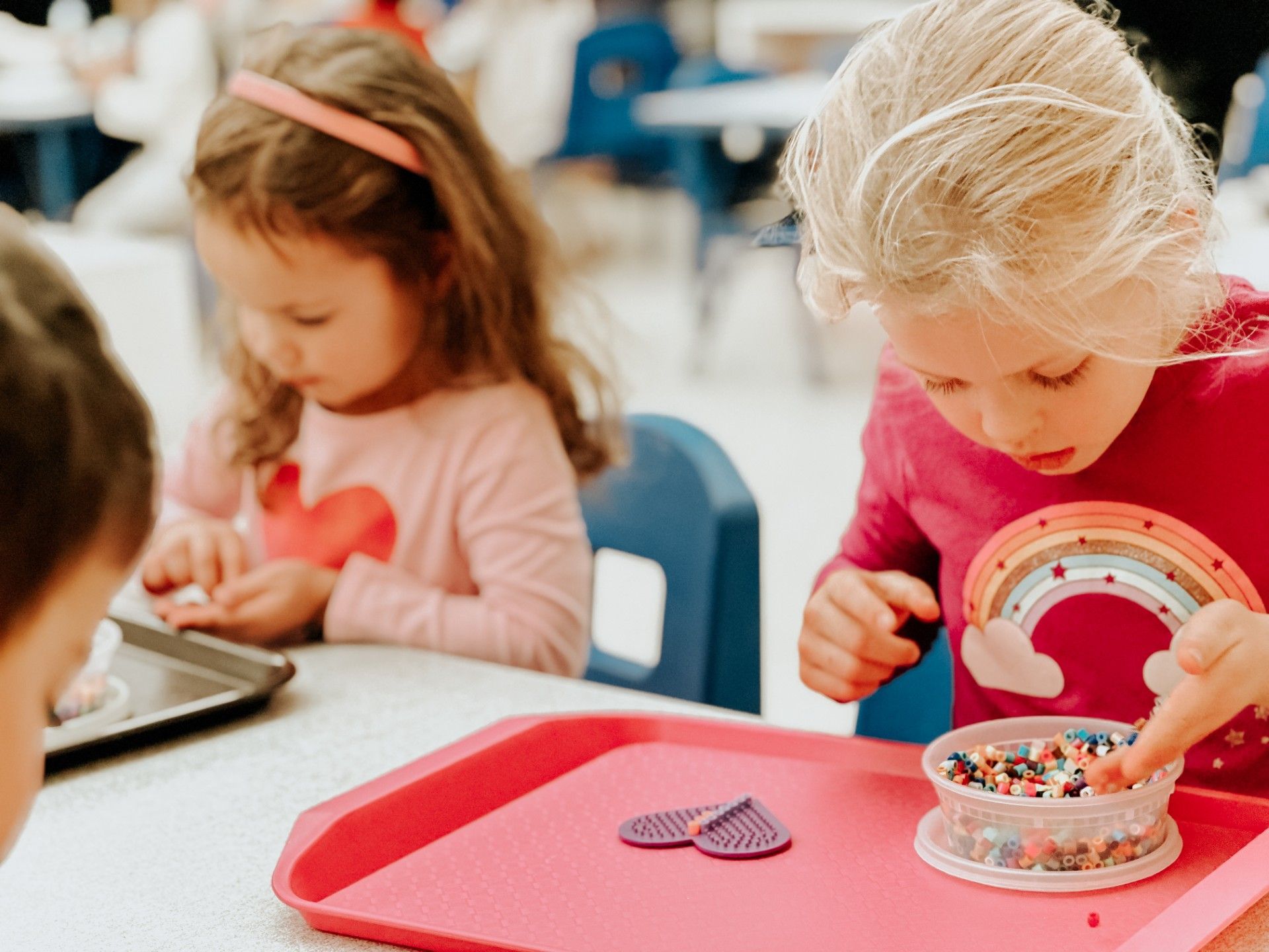 Child placing beads on a heart-shaped bead frame.