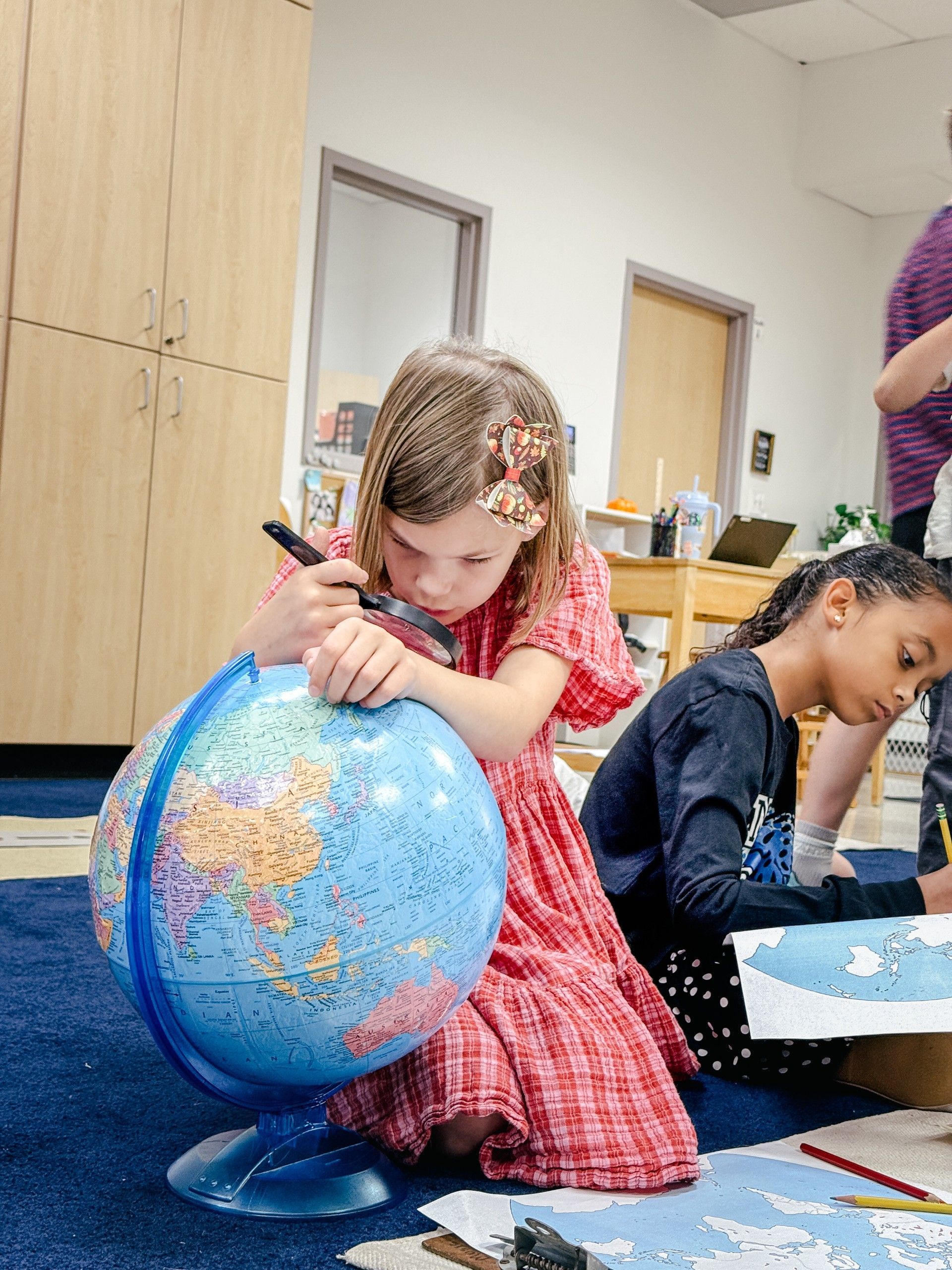 Two children reading together at a library table, both focused on the open book.