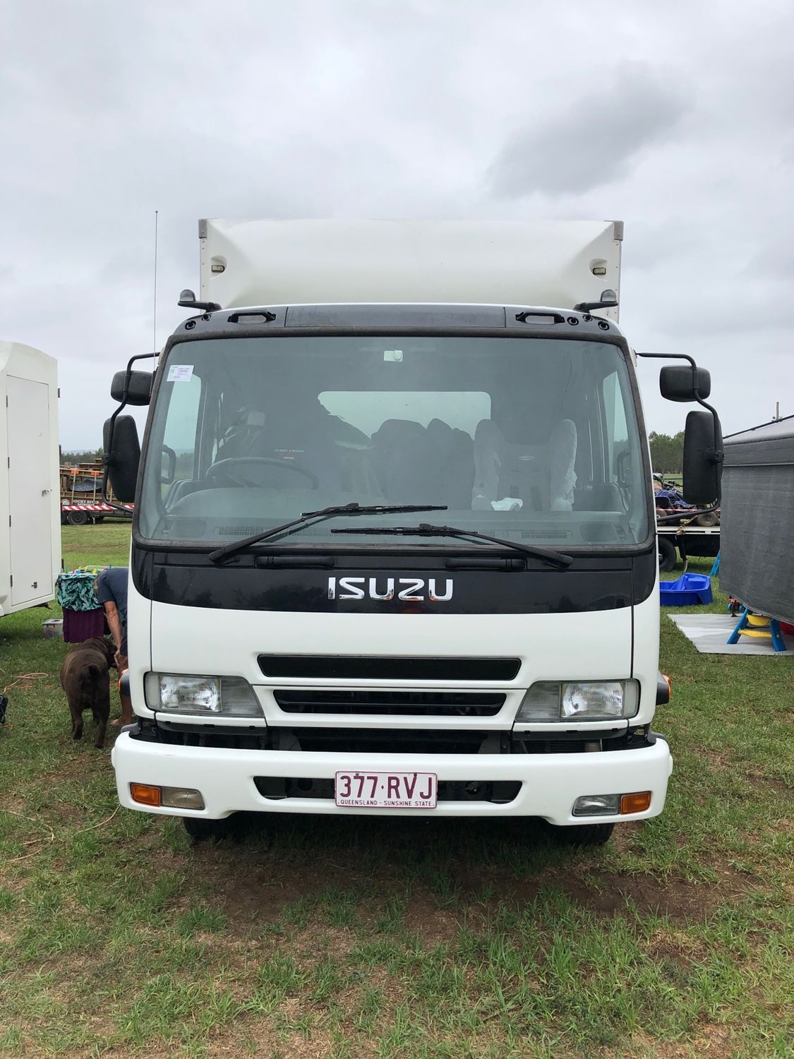 Front view of a white Isuzu truck parked on grass outdoors