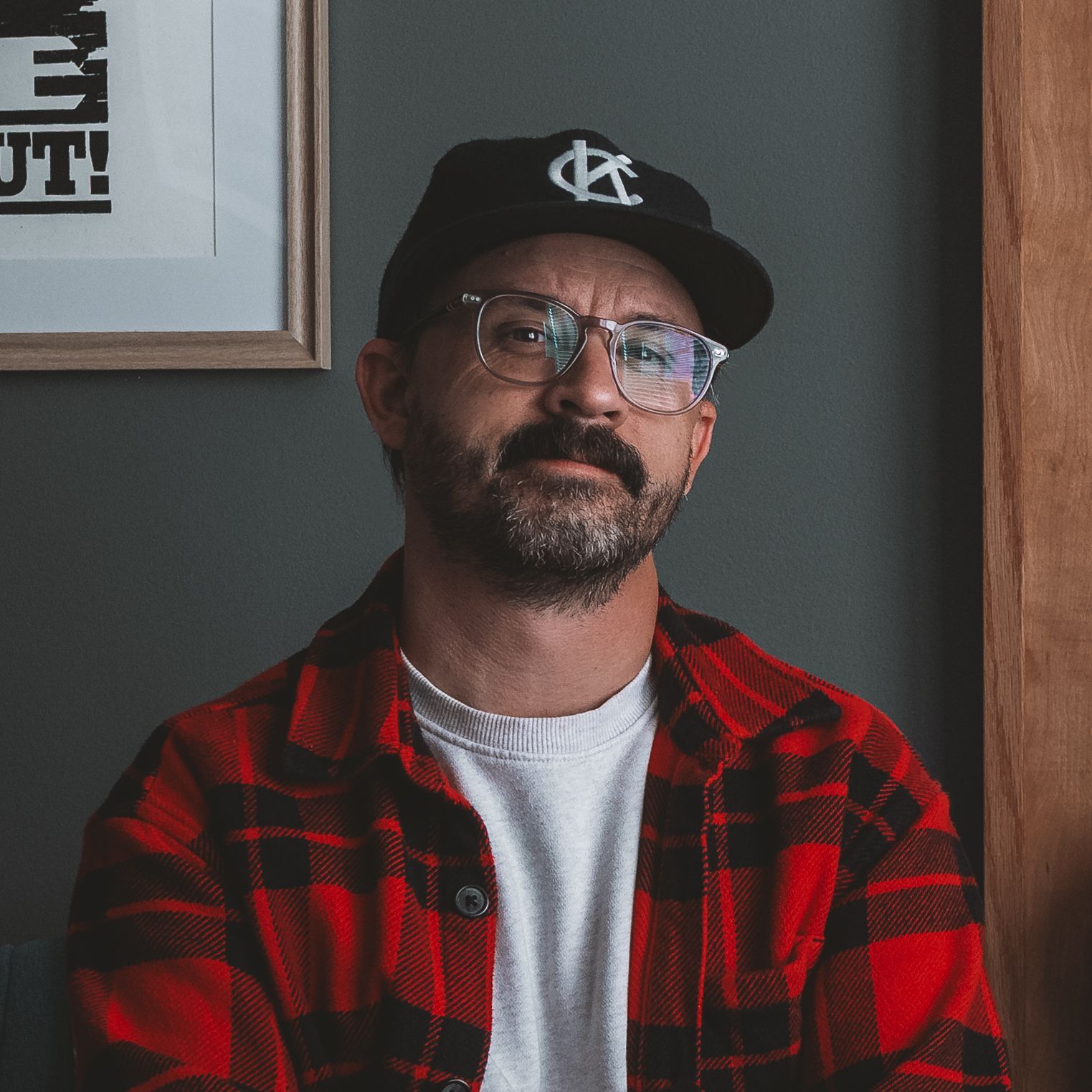 A man wearing a plaid jacket and white shirt is smiling