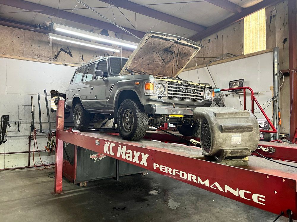 A car is sitting on a lift in a garage with its hood up.