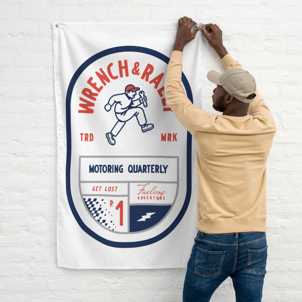 A man is hanging a banner that says wrench & race