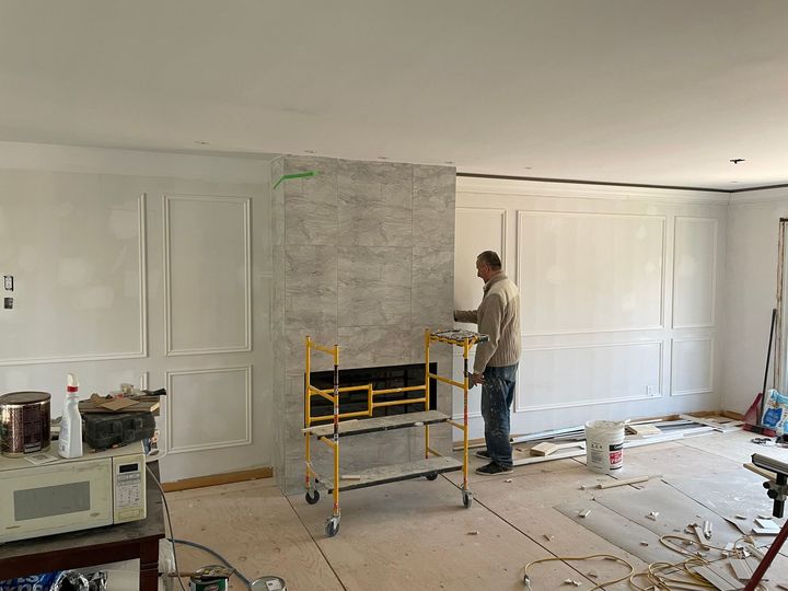 A man is working on a fireplace in a living room.