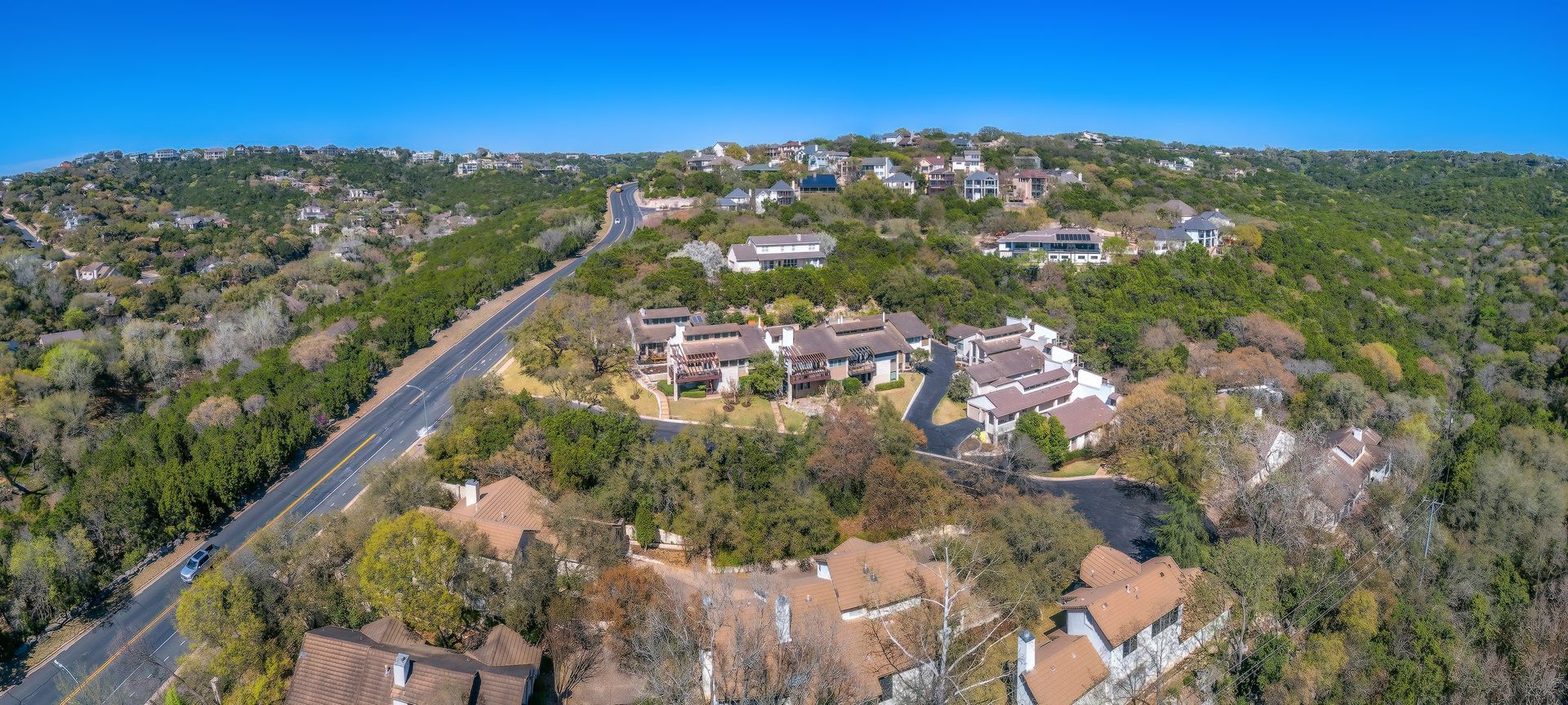 An aerial view of a residential area surrounded by trees and a road.