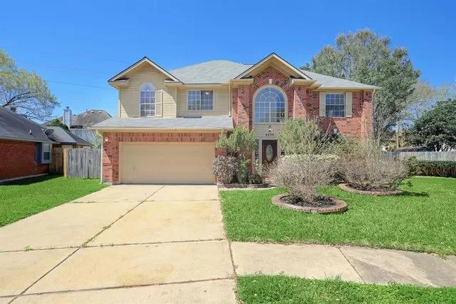 A large brick house with a large driveway and a large garage.