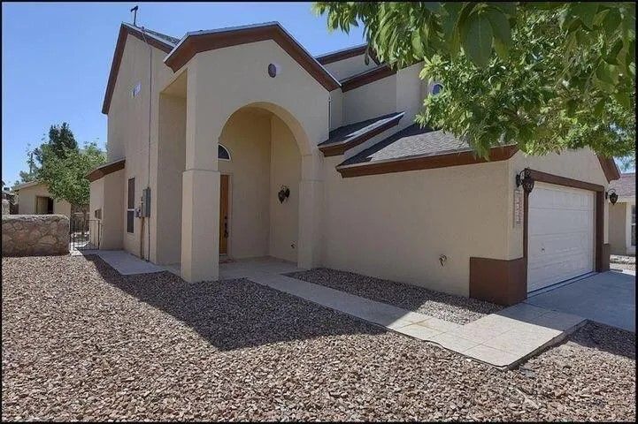 A house with two garages and a tree in front of it