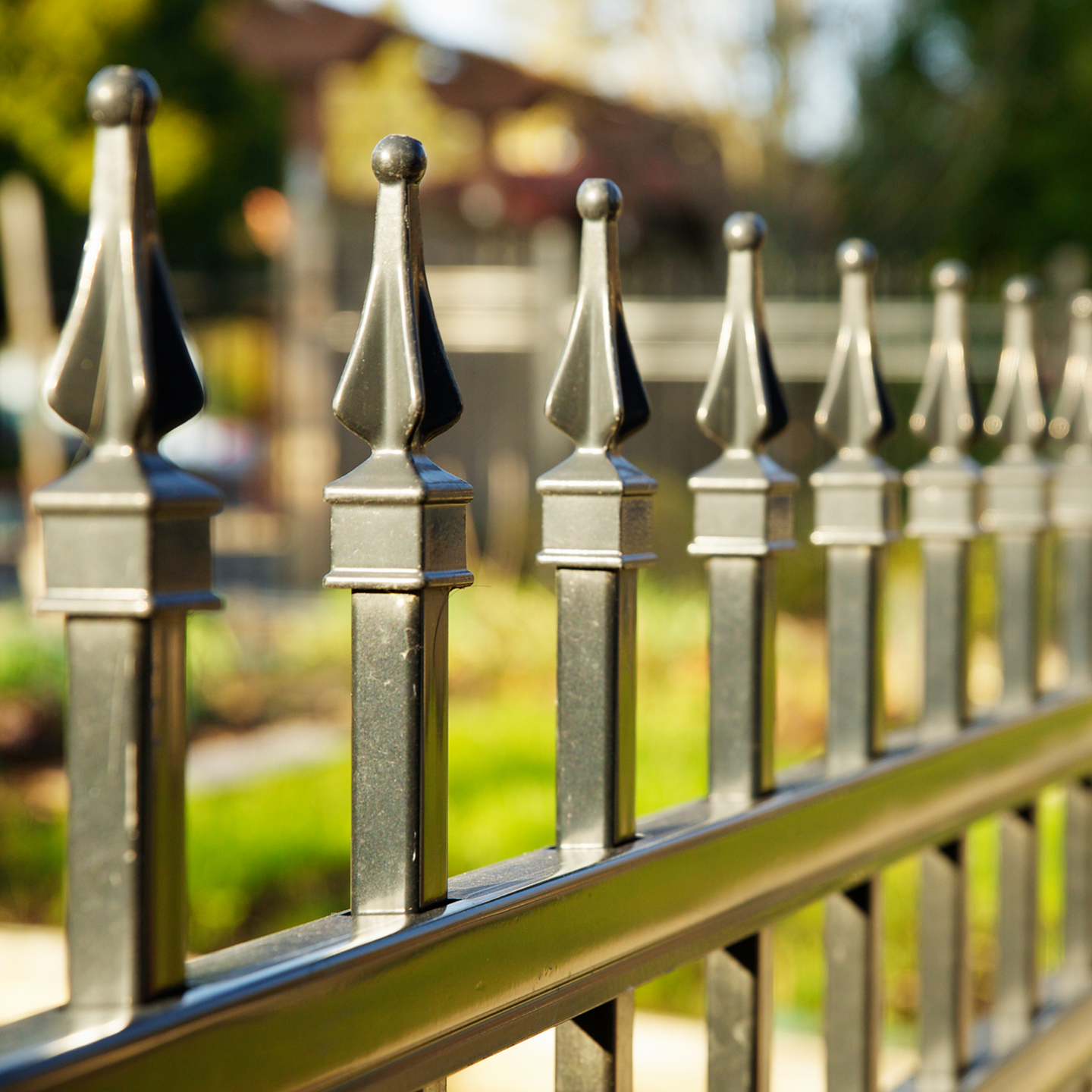 A close up of a metal fence with a house in the background