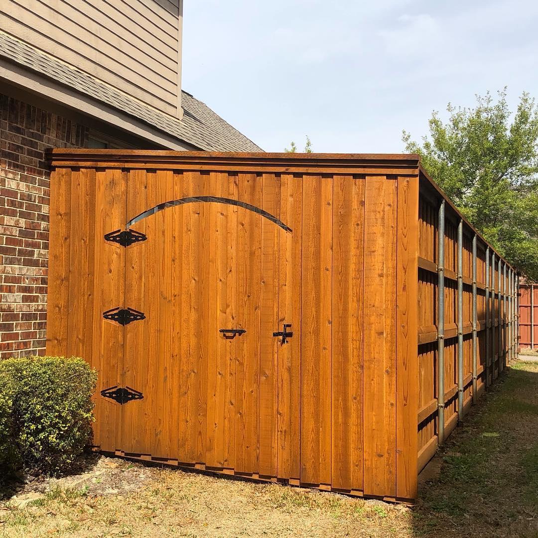 A wooden fence is sitting next to a brick building.