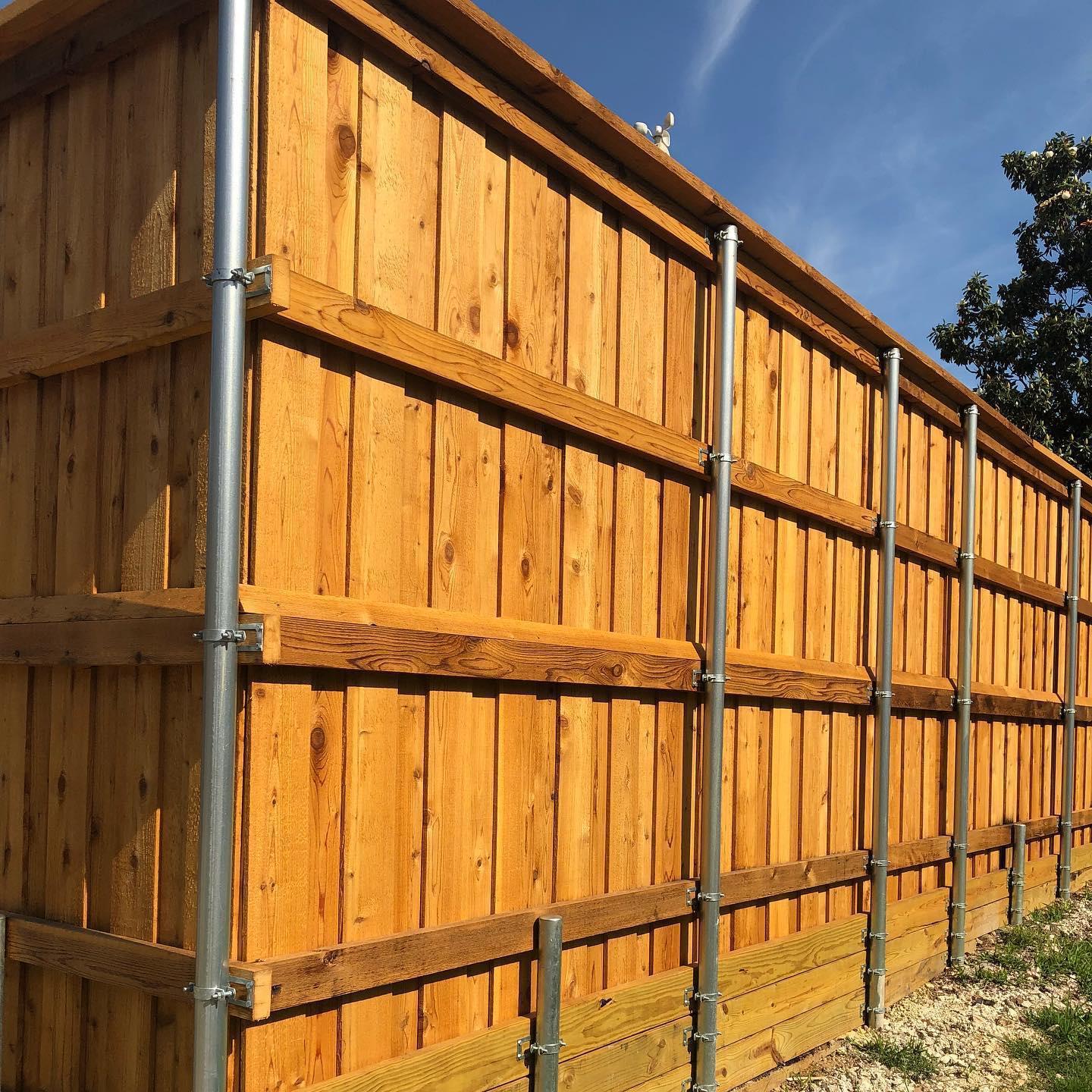A wooden fence with metal poles attached to it