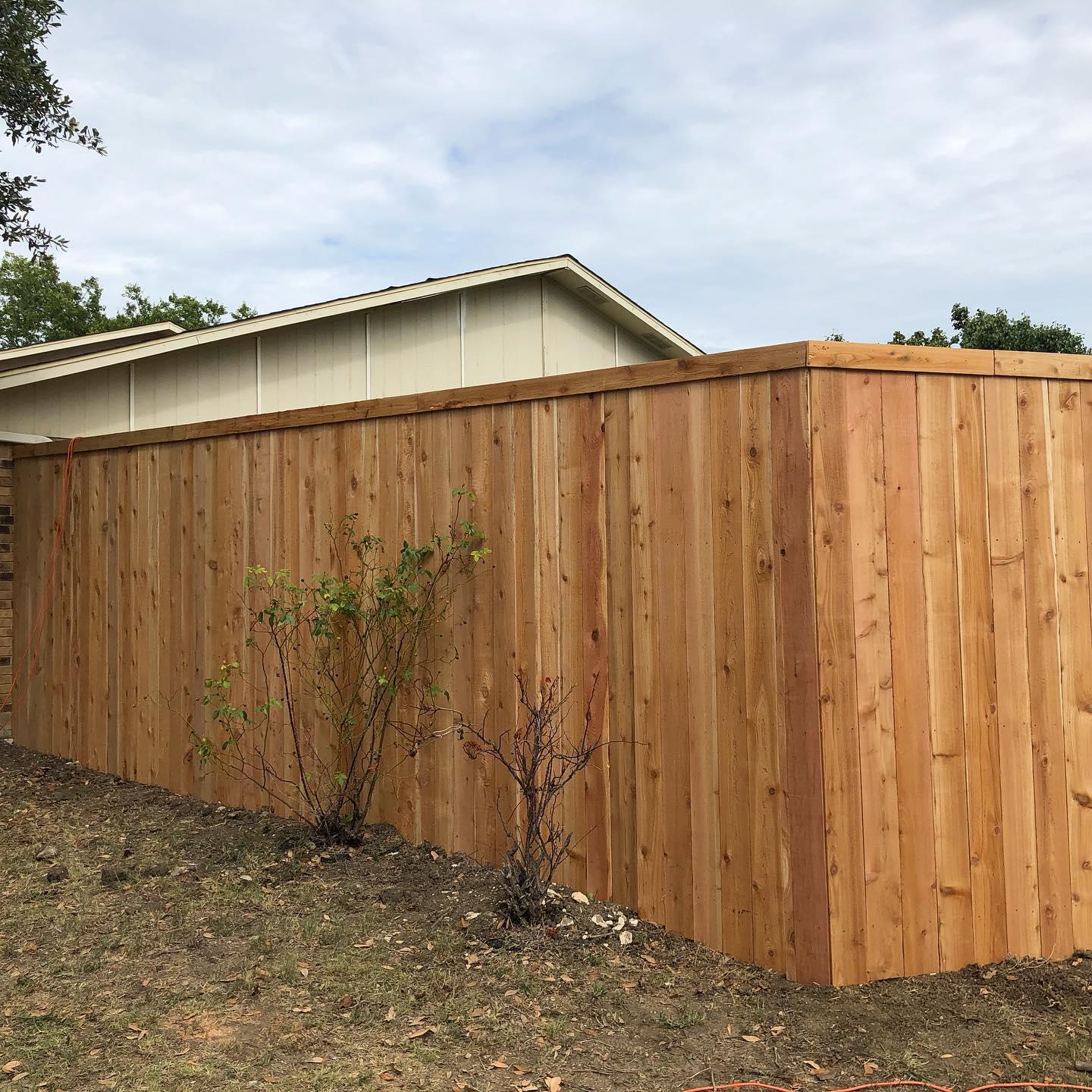 A wooden fence is in the backyard of a house.