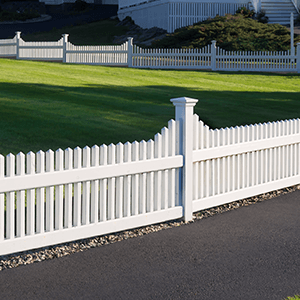 A white picket fence surrounds a lush green field