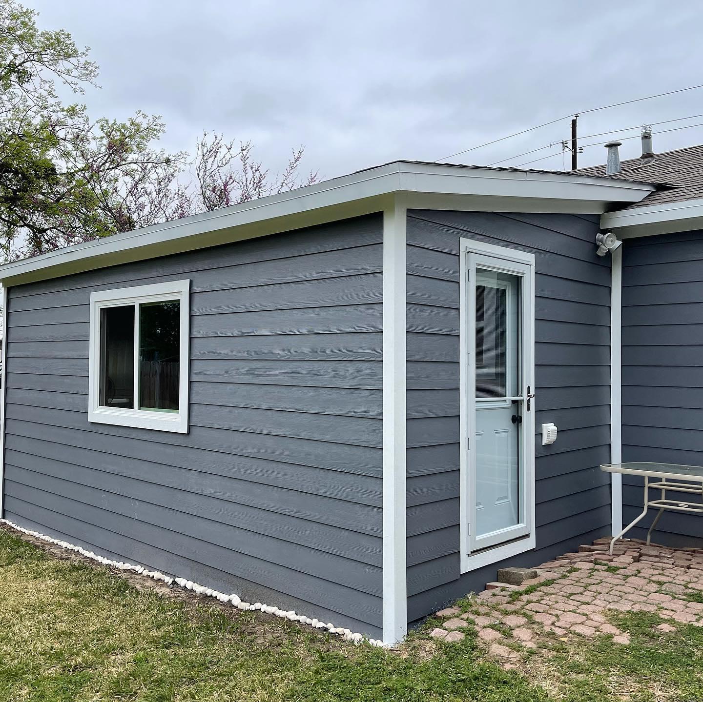 A small gray house with a white door and window.