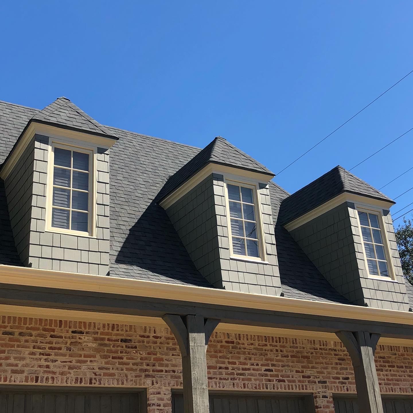 A brick house with a gray roof and white windows