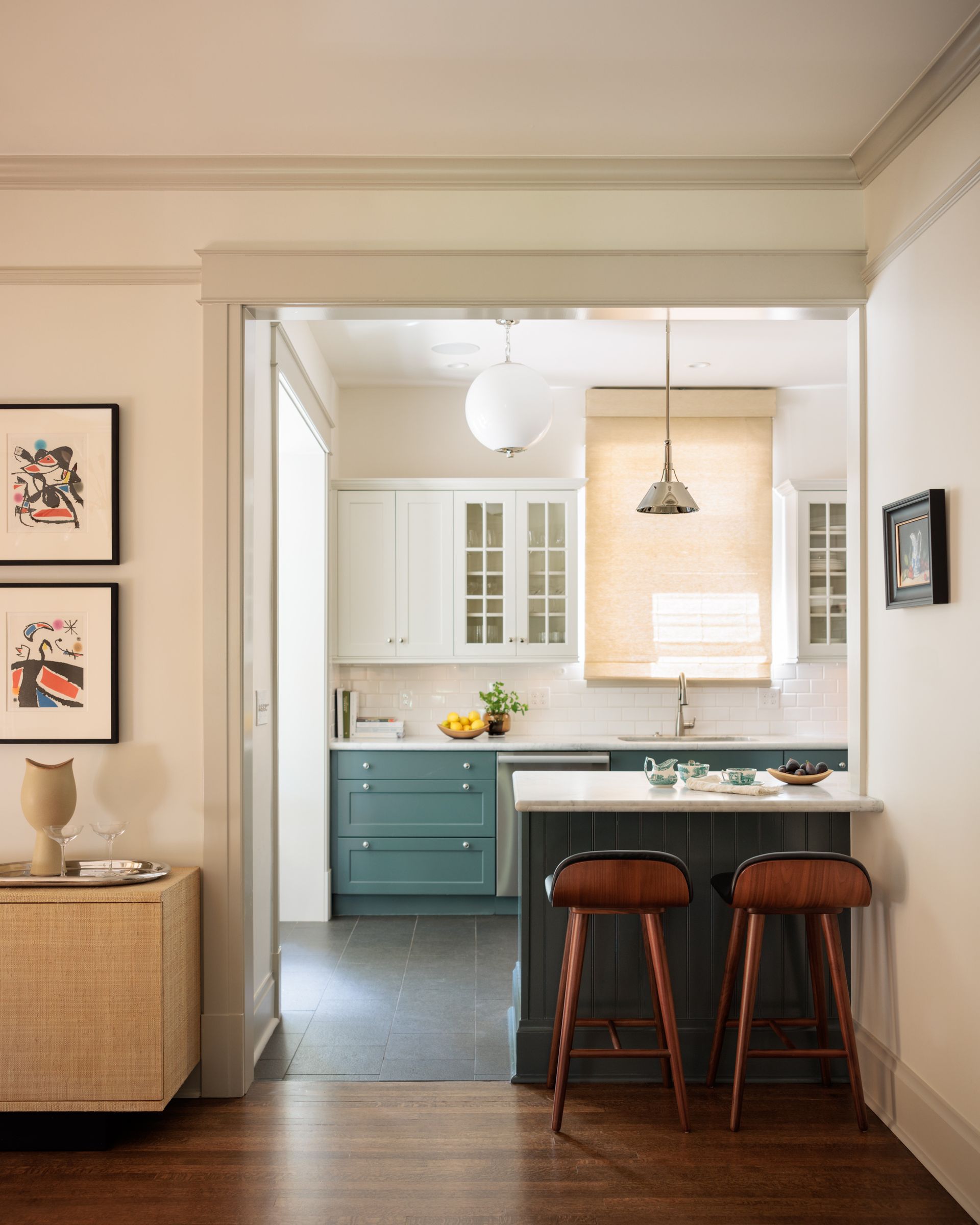 A kitchen with roman shades, blue cabinets and a white counter top