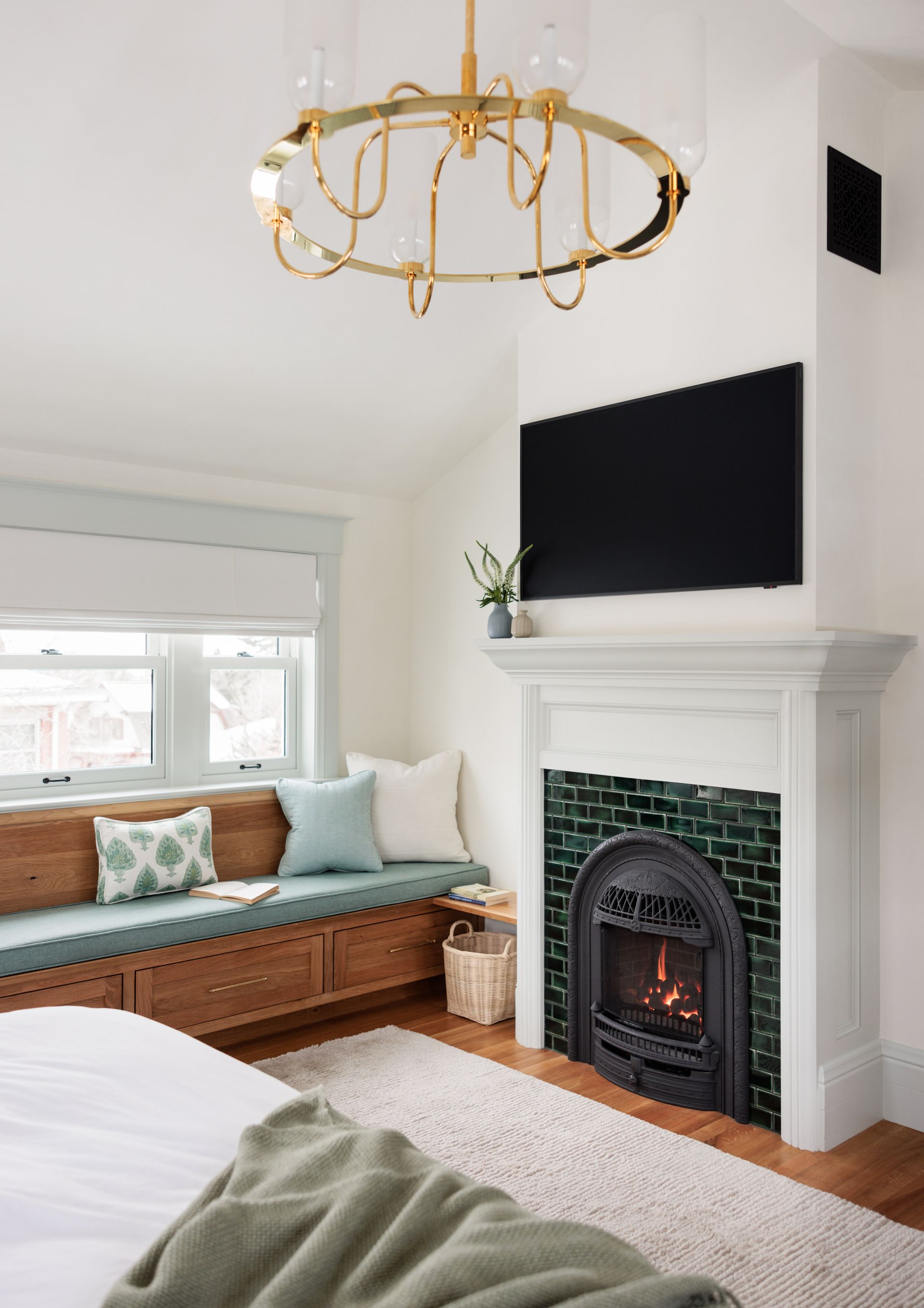 A bedroom with a fireplace , couch , and television and white blackout roman shades