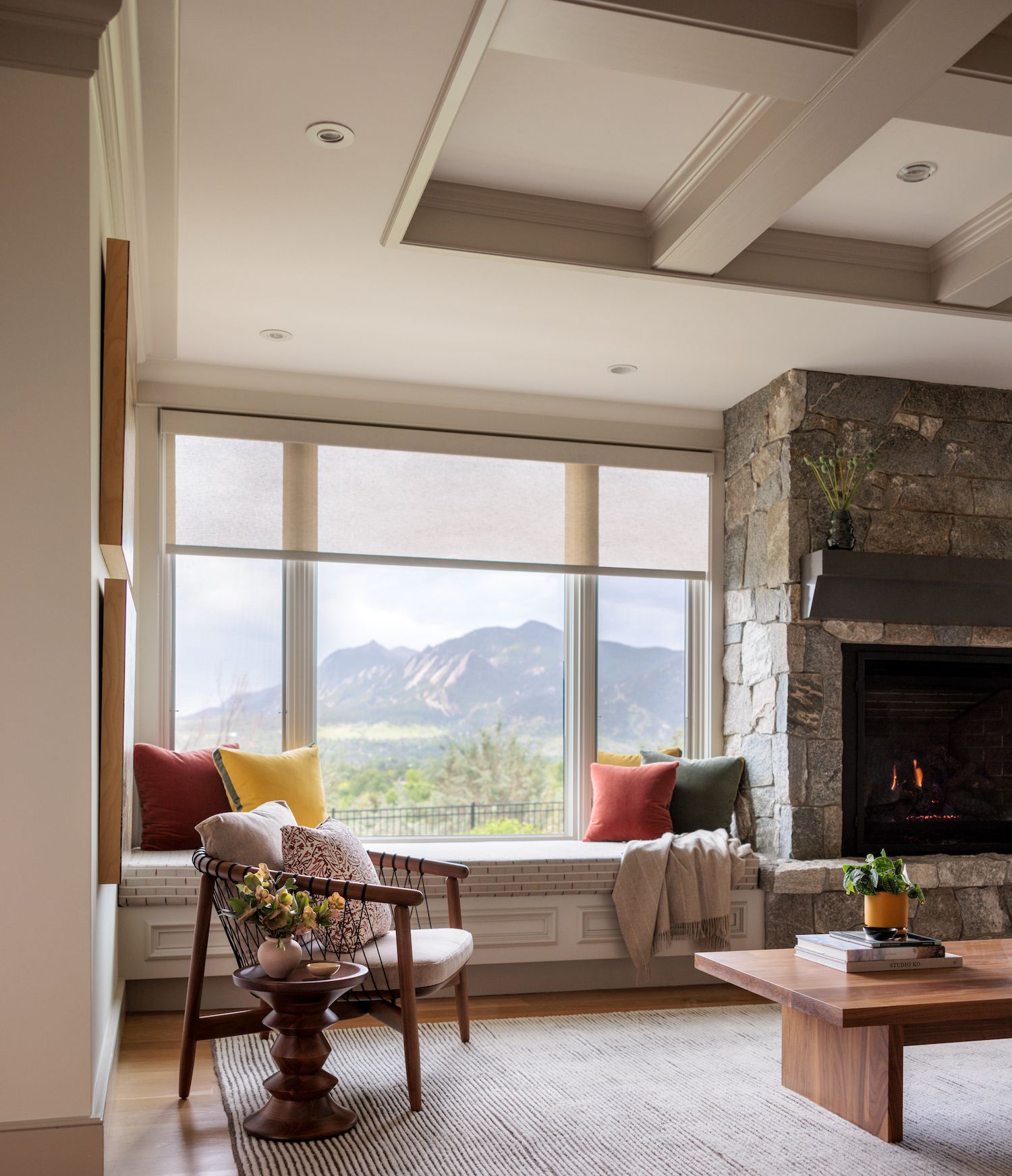 A living room with a fireplace and a window seat with picture window roller shades