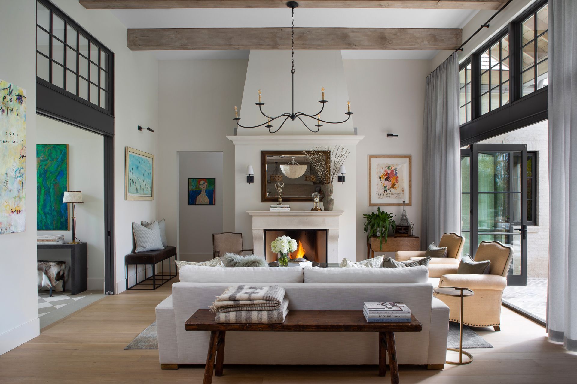 A living room filled with furniture and a fireplace white drapes over black windows