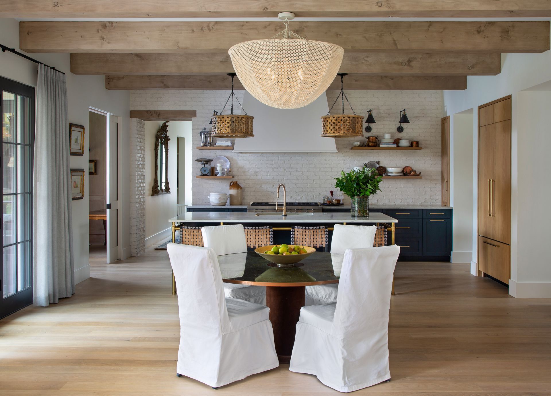 A kitchen with a table and chairs and a chandelier hanging from the ceiling dove gray drapes over french doors